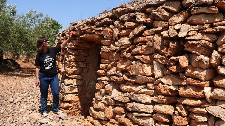 Maria Santiago, membre de la Plataforma Sostenible Camp, mostrant una barraca de pedra seca, afectada pel PDUAE, al terme municipal de Vila-rodona, a l'Alt Camp.