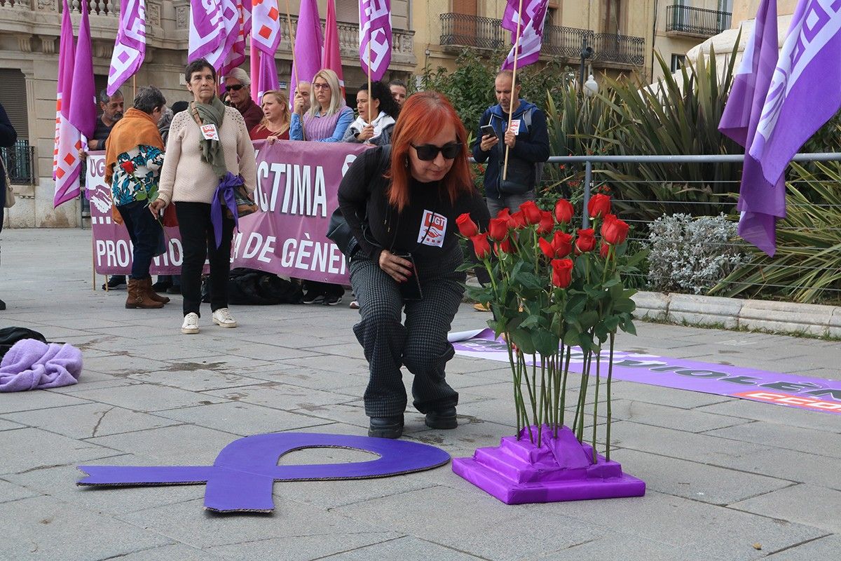 Una dona col·loca una rosa per homenatjar a les víctimes de violència masclista