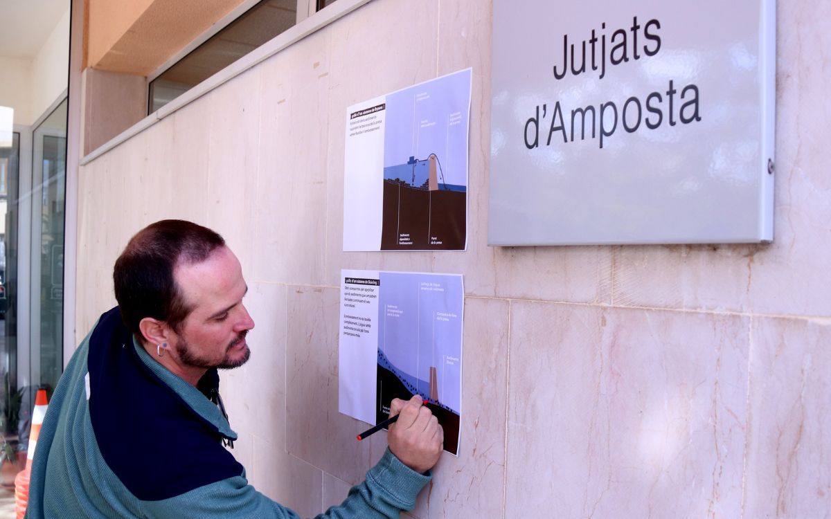 El president de l'associació Sediments amb cartells il·lustrats de la querella contra Endesa i la CHE