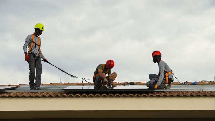 Un grup d'operaris instal·len panells solars en un habitatge