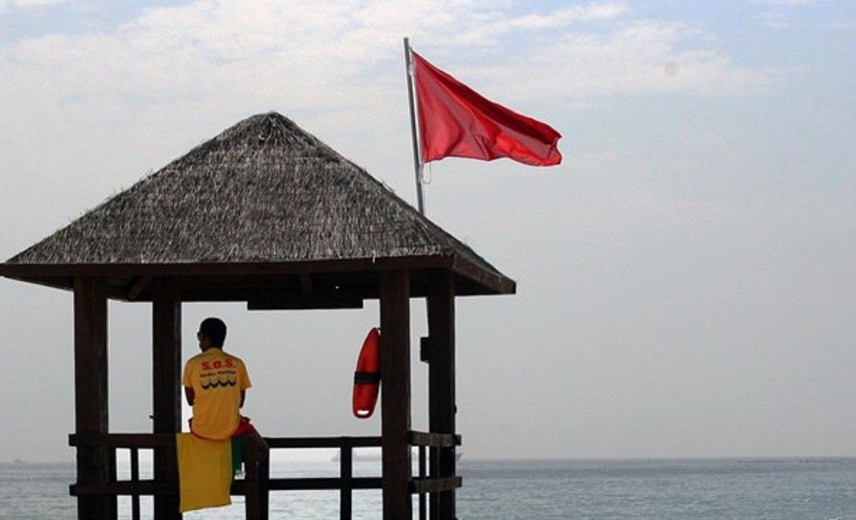 Un socorrista i una bandera vermella en una platja.